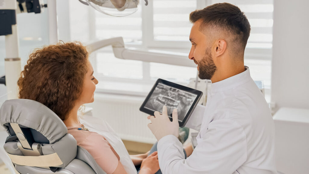 Mulher vendo tablet em que seu dentista esta mostrando.