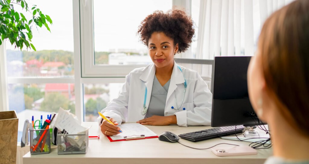 Mulher em sua mesa de trabalho, fazendo atendimento ao paciente.