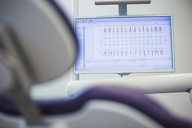 cadeira de consultório odontológico com tela de computador ao fundo.