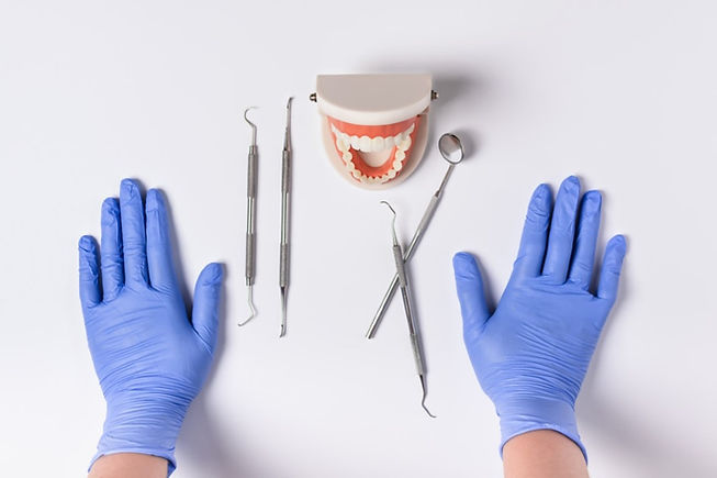 Tratamento odontológico. Dentista mostrando as luvas, uma prótese dentária e equipamentos para tratamentos odontológicos.