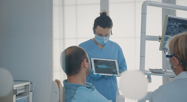 auxiliar de dentista mostrando imagem radiológica de diagnóstico para o paciente