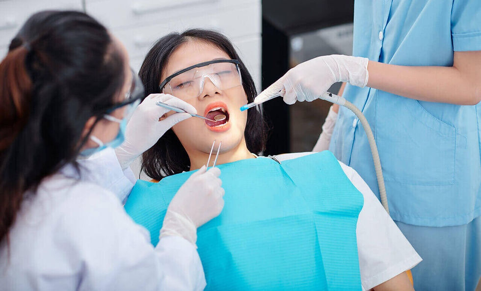 dentista verificando os dentes do paciente enquanto a auxiliar de dentista segura um dispositivo de sucção dentária