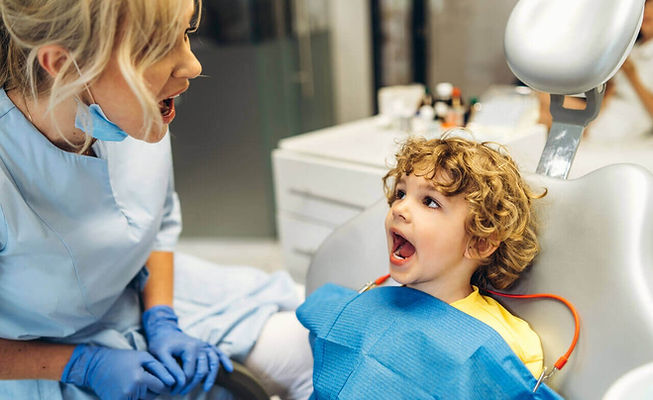 odontopediatra instruindo seu paciente menino no consultório odontológico