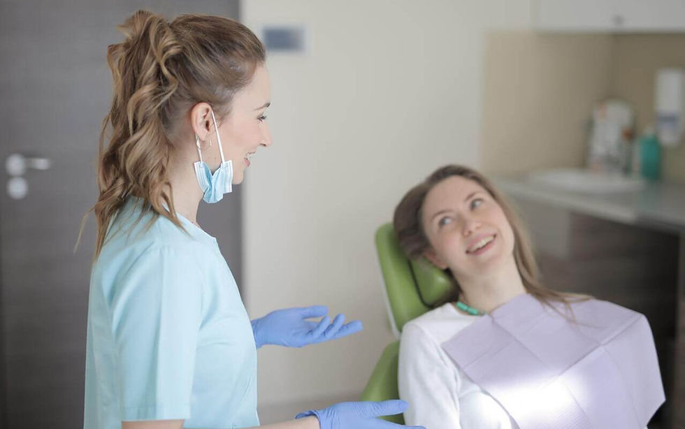 Uma dentista conversa com uma paciente em consultório