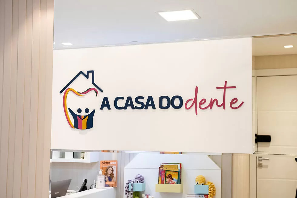 Recepção moderna de consultório odontológico com tons neutros, madeira e iluminação aconchegante.